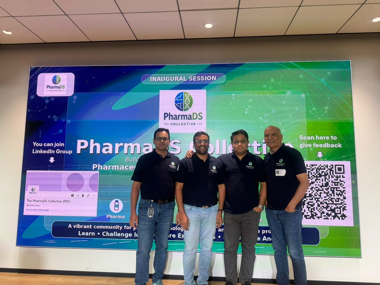 Four founding members of the PharmaDS Collective in branded polo shirts, standing in front of the inaugural session screen.